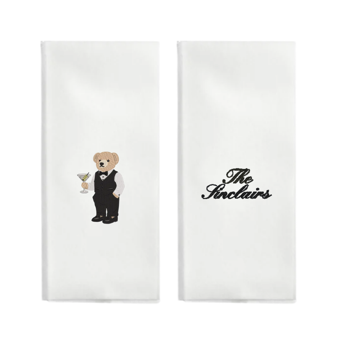 Two white napkins with a teddy bear and 'The Stelains' logo on a white background